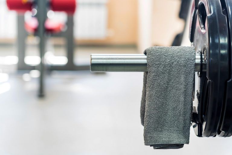 grey towel hangs on barbell in gym URG9LNP 9 768x513