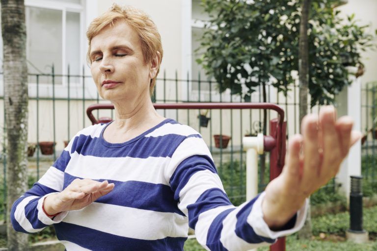 senior woman doing tai chi exercises DENAFH7 768x512