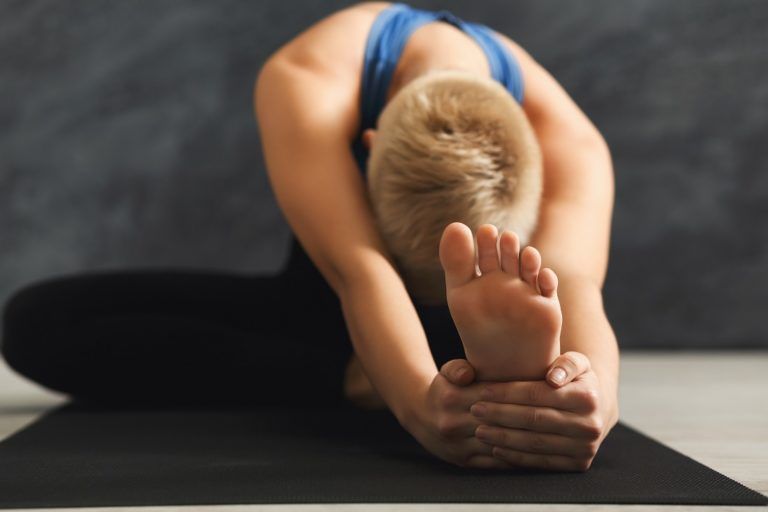 unrecognizable fitness woman stretching at grey PCESUKT 2 768x512