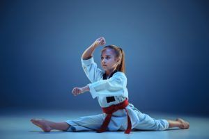 young girl training karate on blue background PYAMLMQ 1 300x200