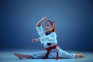 young girl training karate on blue background PYAMLMQ 3 300x200