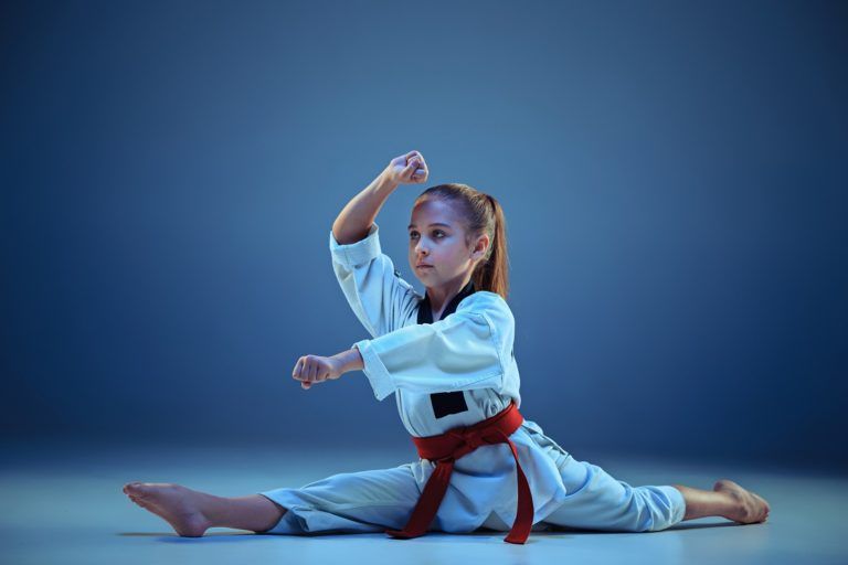 young girl training karate on blue background PYAMLMQ 768x512