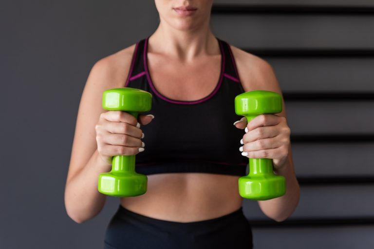 fitness girl lifting dumbbell in the gym GMJ7PST 768x513